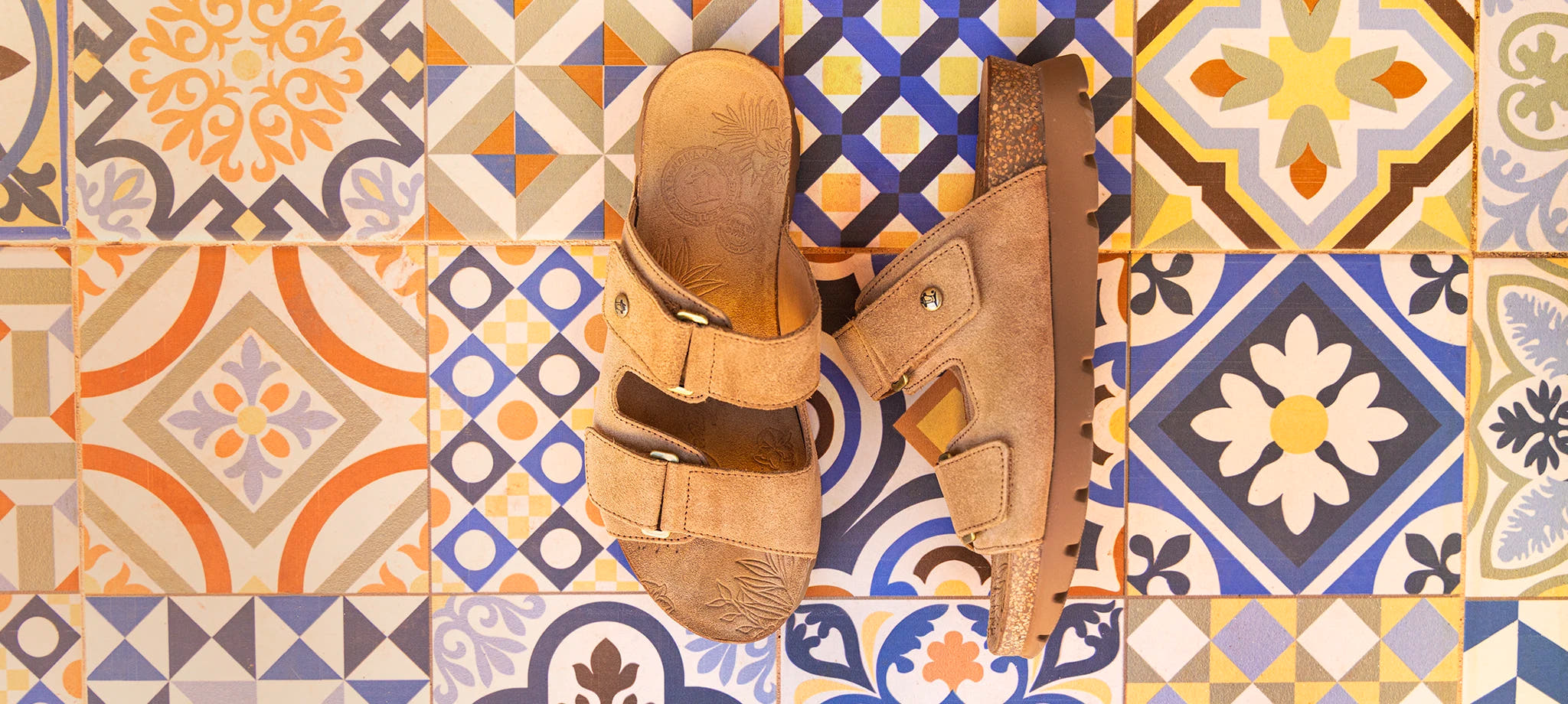 Sandalias Panama Jack Sade de mujer sobre fondo de azulejos decorativos